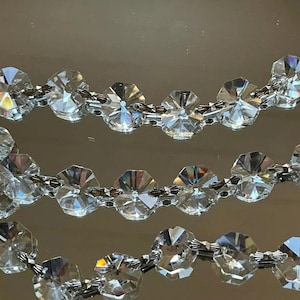 May include: A strand of crystal beads with a silver chain connecting them. The beads are faceted and reflect light.