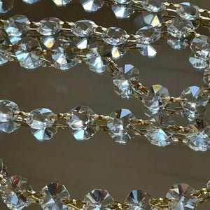 May include: A strand of crystal beads strung on gold wire. The beads are faceted and reflect light.