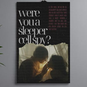 May include: A black poster with the text "were you a sleeper cell spy?" in white. The poster has a torn section revealing a photo of two people. Additional text in pink is also present.