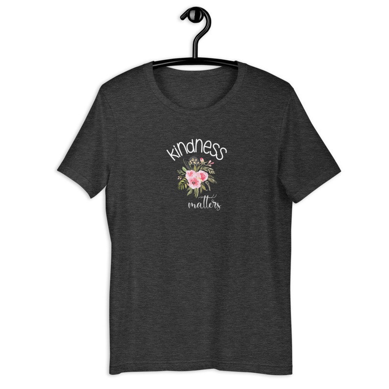 May include: Dark heather grey t-shirt with a white floral design and the text "kindness matters".