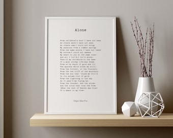 May include: A white framed print with a black and white poem titled "Alone" by Edgar Allan Poe. The poem is printed in a typewriter font and includes lines like "From childhood's hour I have not been as others were" and "Then-in my childhood-in the dawn of a  soft story."