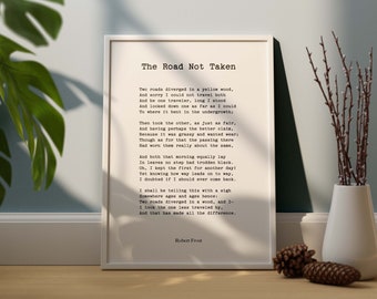 May include: A framed print of Robert Frost's poem "The Road Not Taken" in a minimalist style. The text is in black on an off-white background, set in a white frame. A vase with branches and a pinecone are next to the frame.
