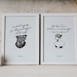 May include: Two framed black and white prints with quotes about beauty and longing. The left print features a bust sculpture and the quote "morbid longing for the picturesque at all costs". The right print features a bust sculpture and the quote "Beauty is Terror. Whatever we call beautiful we quiver before it". Both prints are signed "Donna Tartt".