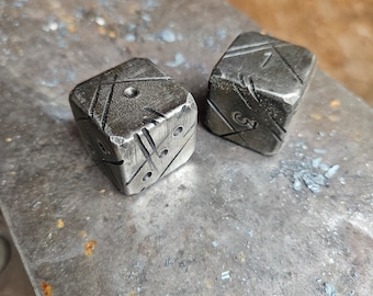Puede incluir: Dos dados de metal con los números 1 y 3 en ellos. Los dados están sobre una superficie de metal.