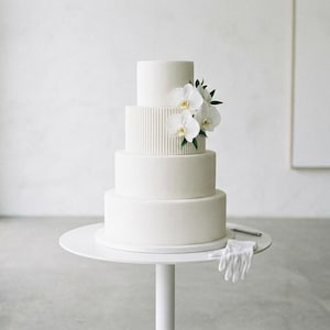 Könnte beinhalten: Ein Set aus drei Keramikbechern mit gesprenkelter, matter Oberfläche. Die Becher sind in Creme-, Hellgrau- und Dunkelgrautönen gehalten. Jeder Becher hat ein schlichtes, minimalistisches Design, ideal für Kaffee oder Tee.