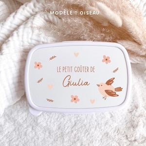 May include: A white rectangular lunch box featuring a printed design of a small bird, pink flowers, and hearts. The text reads "LE PETIT GO&Ucirc;TER DE Giulia" in brown lettering. The lid is smooth and white, with a clean, simple, and functional design.
