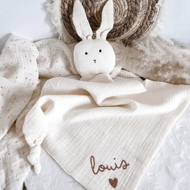 Doudou lapin personnalisé en gaze de coton.
Personnalisable au prénom de votre enfant avec un petit motif au choix sous le prénom.