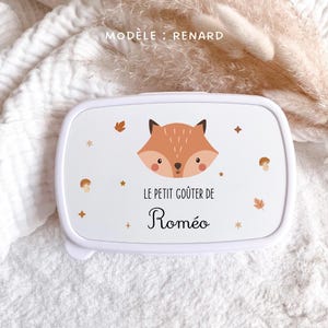 May include: A white rectangular lunch box featuring a cartoon fox face, small brown mushrooms, and autumn leaves. The text reads "MOD&Egrave;LE : RENARD" at the top and "LE PETIT GO&Ucirc;TER DE Rom&eacute;o" in the center, printed in black and brown lettering.