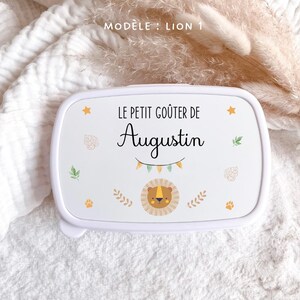 May include: A white rectangular snack box featuring the text LE PETIT GO&Ucirc;TER DE Augustin, a small lion illustration, colorful bunting, and scattered leaf and paw print motifs. The design is centered on the lid of the plastic container.