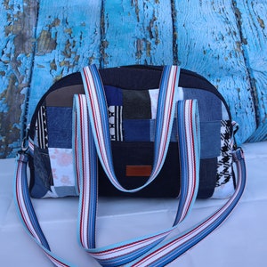 Könnte beinhalten: Eine blaue Jeans-Patchwork-Tragetasche mit einem weißen und roten Schulterriemen. Die Tasche besteht aus verschiedenen Jeans-Flicken, die in einem zufälligen Muster zusammengenäht sind.