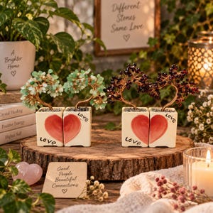 May include: Two pairs of decorative wire bonsai trees with gemstone leaves in square white ceramic pots. Each pot features half of a painted red heart and the word Love. One pair has light green stones, the other has dark red stones.