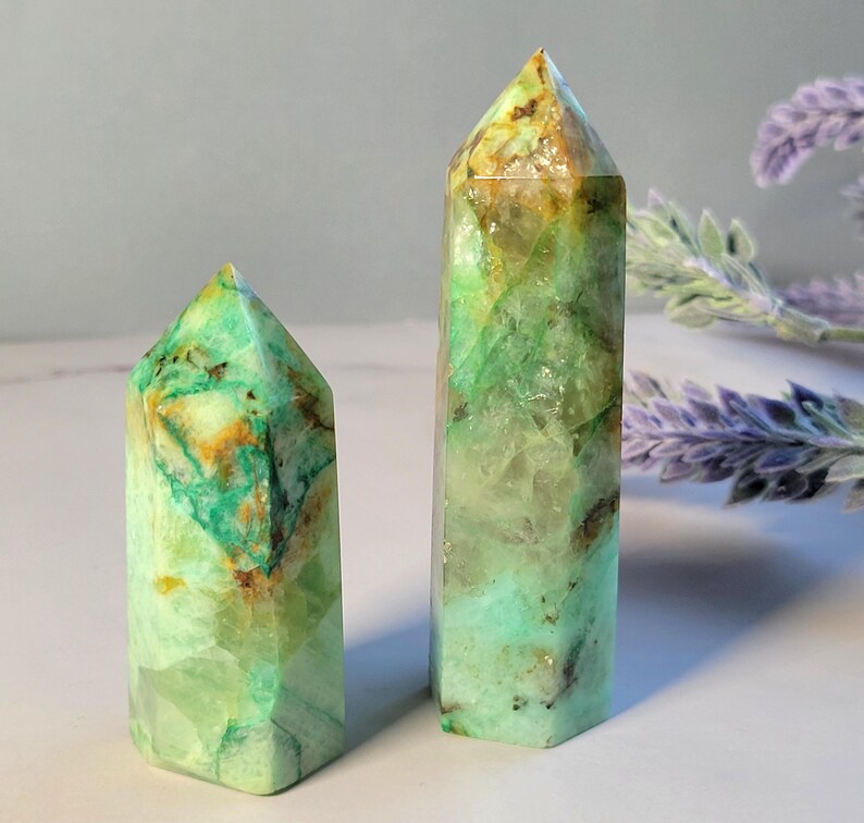May include: Two polished crystal points with a hexagonal shape. The stones feature a vibrant mix of translucent mint green, opaque teal, and warm amber-colored inclusions throughout their faceted surfaces, ending in a sharp, pointed apex.