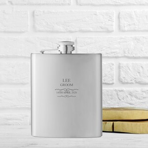 May include: Silver flask with a personalised inscription that reads "Lee Groom 14th April 2020".