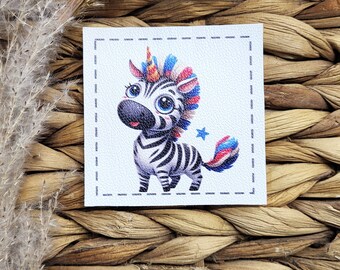 May include: A square patch featuring a cartoon zebra with a unicorn horn and colourful mane and tail. The zebra has black and white stripes, large blue eyes, and a small blue star. The patch is on a textured white background.