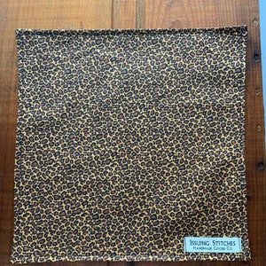 May include: A brown and black leopard print fabric square with a white tag that reads "Issuing Stitches Handmade Goods Co."