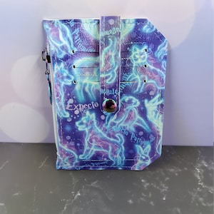 May include: A purple and blue card holder with a zipper and a strap. The card holder has a pattern of glowing white lines and the text "Expecto Patronum" repeated on it.