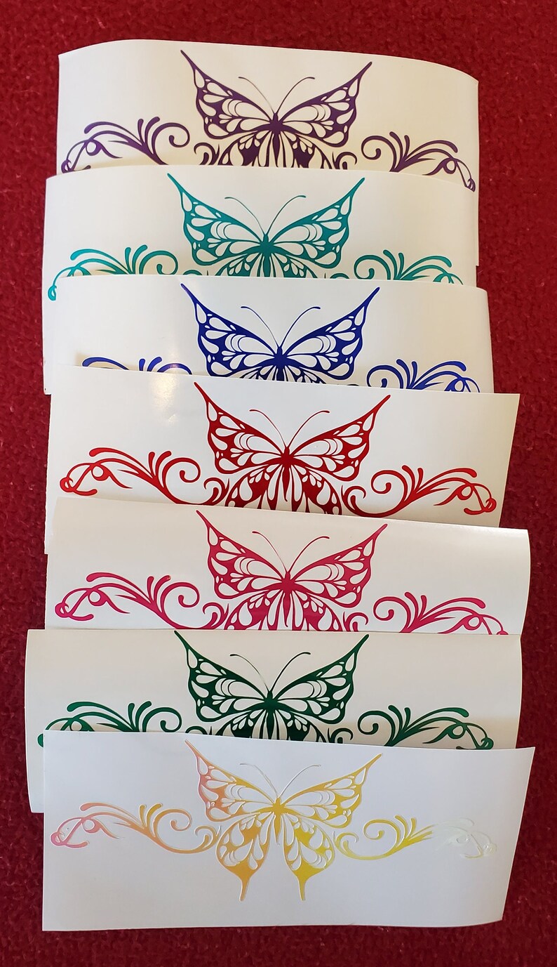 May include: Set of seven butterfly decals in various colors, including purple, teal, blue, red, pink, green, and yellow. Each decal features a stylized butterfly with intricate details and a swirling floral design.