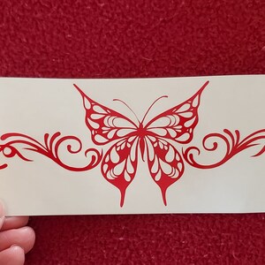May include: Red vinyl decal of a butterfly with intricate details and swirls. The butterfly is centered on a white background.