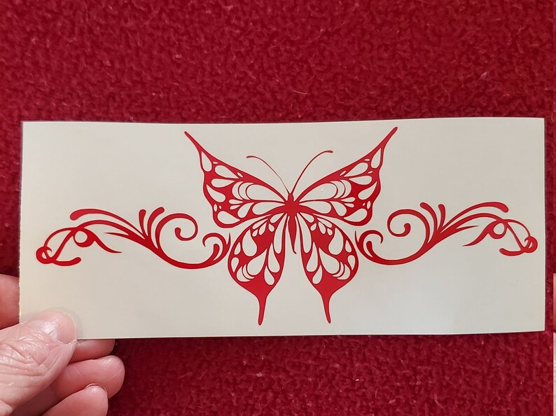 May include: Red vinyl decal of a butterfly with intricate details and swirls. The butterfly is centered on a white background.