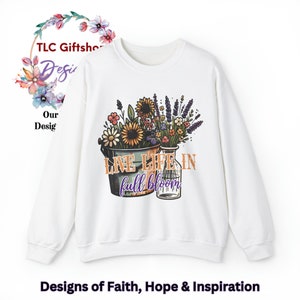 May include: White sweatshirt with a floral design and the text "LIVE LIFE IN full bloom". The flowers are in a bucket and a jar.