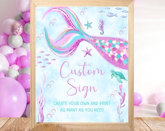Può includere: Un cartello incorniciato con un design a coda di sirena nei toni del rosa, turchese e oro. Il cartello recita "Custom Sign" e include illustrazioni di creature marine. Lo sfondo è azzurro con bolle.