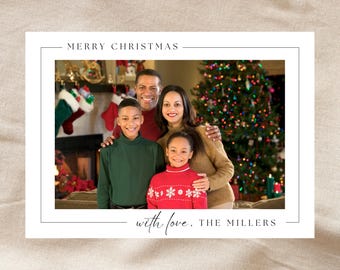 May include: A rectangular holiday greeting card featuring a photograph of a family of four. The text MERRY CHRISTMAS is printed at the top, and the text with love, THE MILLERS is printed at the bottom, both in a thin, black, serif font.