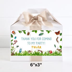 May include: White party favor box with a beige ribbon bow. The box features a label with watercolor illustrations of insects and the text "THANK YOU FOR COMING TO MY PARTY! TYLER". The label measures 6" x 3".