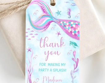 Puede incluir: Una etiqueta de regalo rectangular con fondo de acuarela azul claro que presenta una cola de sirena rosa y turquesa, un caballito de mar, una tortuga marina, estrellas de mar y algas. El texto dice thank you FOR MAKING MY PARTY A SPLASH! y Madison.