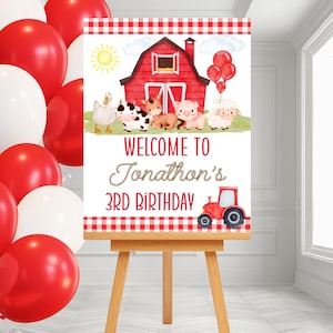 Può includere: Un cartello per una festa di compleanno con un fienile rosso, animali della fattoria e un trattore rosso. Il cartello dice "Benvenuto al 3° compleanno di Jonathan". Palloncini rossi e bianchi sullo sfondo.