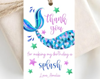 Puede incluir: Una etiqueta de regalo rectangular blanca con un agujero en la parte superior y cordel marrón. La etiqueta presenta una ilustración de cola de sirena azul y morada, estrellas de mar verdes y moradas, y el texto: thank you for making my birthday a splash Love, Amelia.