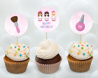 May include: Three cupcakes with pink frosting and colorful sprinkles. Each cupcake has a round pink topper with a different design: a makeup brush, three girls with pink bows, and a bottle of nail polish.