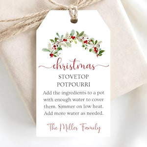 Könnte beinhalten: Ein weißes, rechteckiges Geschenkanhänger-Etikett mit Loch und Bindfaden, verziert mit einem Aquarellkranz aus grünen Blättern und roten Beeren. Der Text lautet: christmas STOVETOP POTPOURRI Add the ingredients to a pot with enough water to cover them. Simmer on low heat. Add more water as needed. The Miller Family.