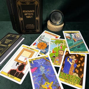 May include: A tarot card deck titled "Renowned Artists Tarot" with a black box and gold lettering. The deck includes several illustrated cards featuring artwork by various artists. A crystal ball sits on a wooden base, and a guidebook is also present.