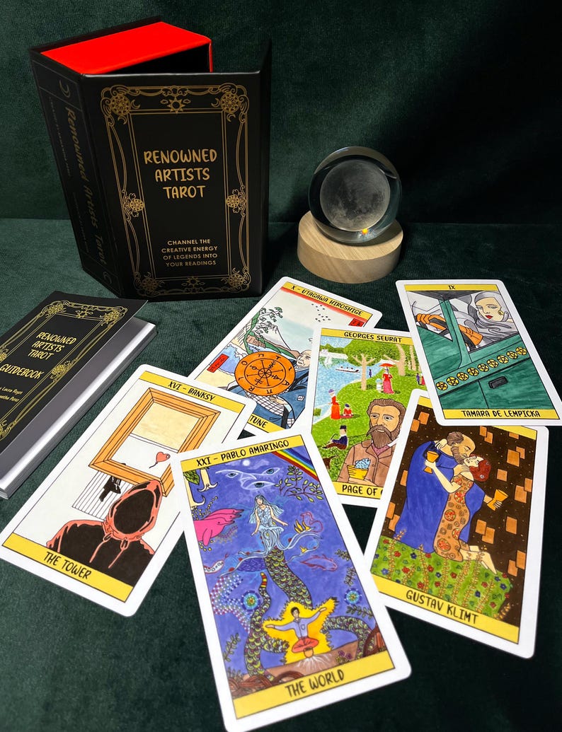 May include: A tarot card deck titled "Renowned Artists Tarot" with a black box and gold lettering. The deck includes several illustrated cards featuring artwork by various artists. A crystal ball sits on a wooden base, and a guidebook is also present.