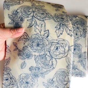 May include: A sheet of white beeswax food wrap with a blue floral pattern. The wrap is made from natural materials and is reusable and compostable.