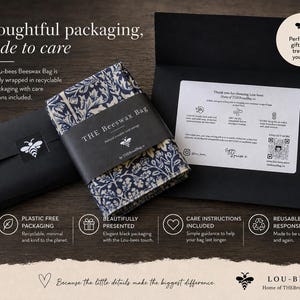 May include: A folded beeswax bag with a dark blue and cream floral pattern, wrapped in a black paper band labeled THE BEESWAX BAG. It is presented with a black envelope containing care instructions, a bee logo, and text about sustainable packaging.
