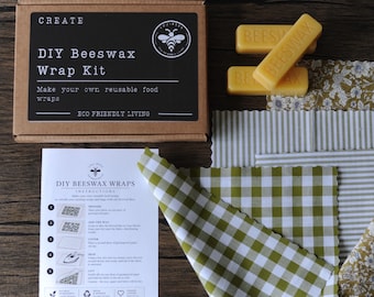 May include: A DIY beeswax wrap kit in a brown cardboard box with a black label reading CREATE DIY Beeswax Wrap Kit. Includes two yellow beeswax bars, a white instruction sheet with five steps, and several fabric squares featuring green gingham.