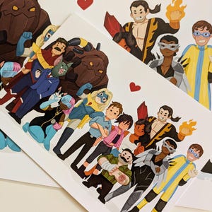 May include: A stack of white art prints featuring a group of cartoon superheroes. The characters are diverse, with various costumes and expressions. Red hearts are scattered across the prints. The artwork is colorful and detailed, with a comic book style.