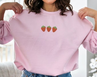 May include: A pink sweatshirt with a small embroidered design of three red strawberries.