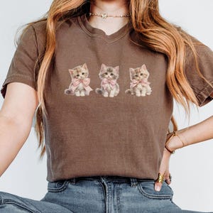 Coquette Shirt Drei kleine Kätzchen Komfortfarben Shirt, niedliche Cottagecore Katzen im Coquette-Stil mit rosa Bögen Graphic Tee Grandmacore Tee