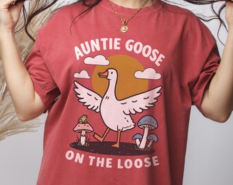 Może przedstawiać: Czerwony T-shirt z grafiką kreskówkowej gęsi i tekstem "Auntie Goose on the Loose".