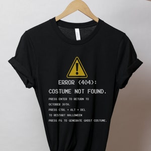 May include: Black t-shirt with a yellow warning sign and the text "ERROR <404>: COSTUME NOT FOUND."  The text below the warning sign reads "PRESS ENTER TO RETURN TO OCTOBER 30TH. PRESS CTRL + ALT + DEL TO RESTART HALLOWEEN PRESS F6 TO GENERATE GHOST COSTUME."