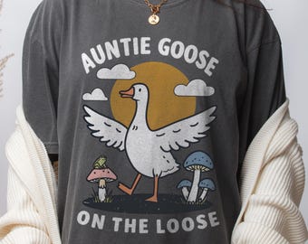 May include: A dark gray t-shirt with a cartoon goose and the text "Auntie Goose on the Loose".