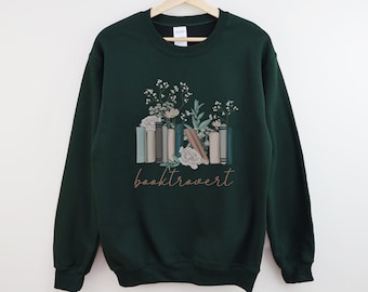 May include: A dark green sweatshirt with a graphic of a stack of books with flowers and the text "booktrovert" printed on the front.