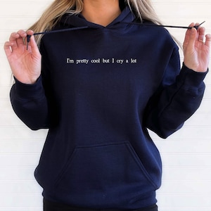 May include: A navy blue hoodie with a white text print that reads "I'm pretty cool but I cry a lot".