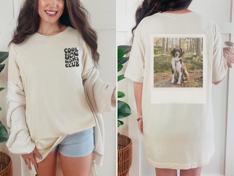 May include: A cream-coloured t-shirt with the text "Cool Dog Moms Club" printed on the front. The back of the shirt features a photo of a brown and white dog in a woodland setting.