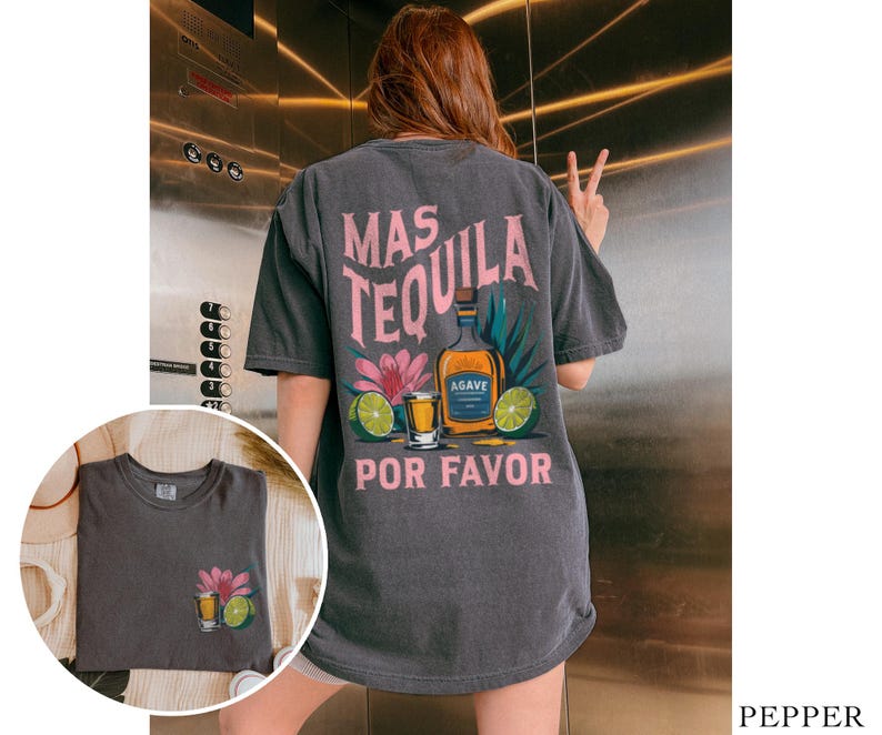 May include: A dark gray t-shirt with a graphic print of a tequila bottle, shot glass, and limes. The text on the shirt reads "Mas Tequila Por Favor".