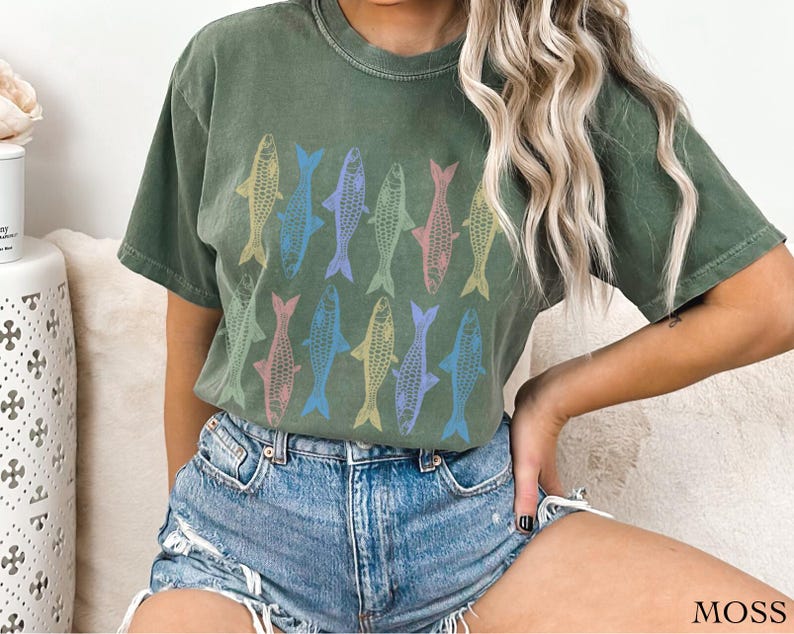 May include: A green t-shirt with a pattern of colorful fish printed on the front. The shirt is made of a soft, comfortable fabric and has a relaxed fit.
