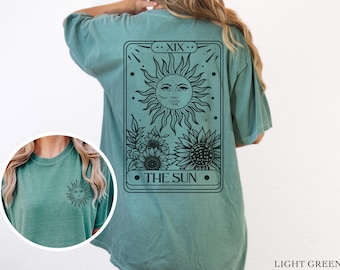 May include: A light green t-shirt with a black and white tarot card design featuring the sun and sunflowers. The card reads "XIX. THE SUN."