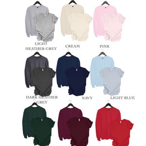 May include: Nine different color combinations of a long-sleeved sweatshirt and a short-sleeved t-shirt. The colors include light heather grey, cream, pink, dark heather grey, navy, light blue, forest green, maroon, and red.